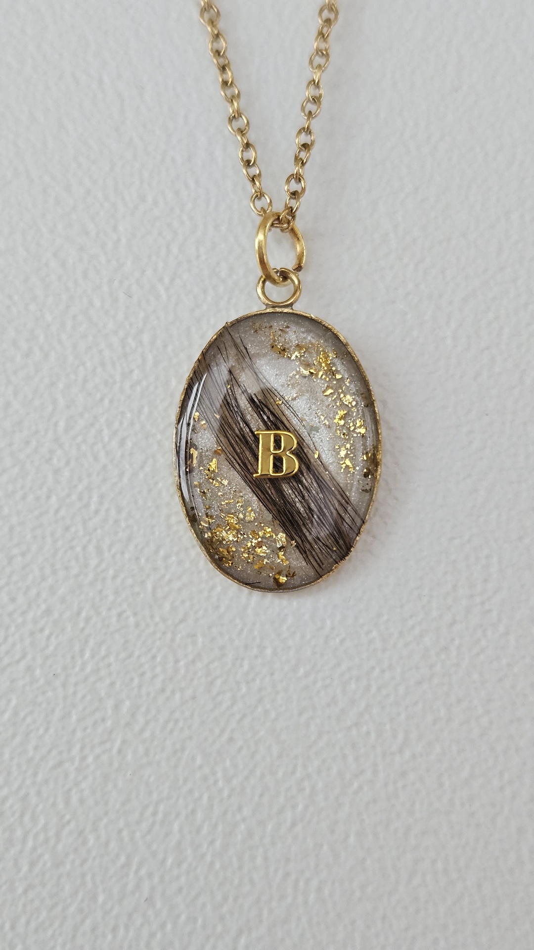 Ovaler Resin-Anhänger mit Tierfell, Blattgold und goldenem Buchstaben B an einer goldfarbenen Kette