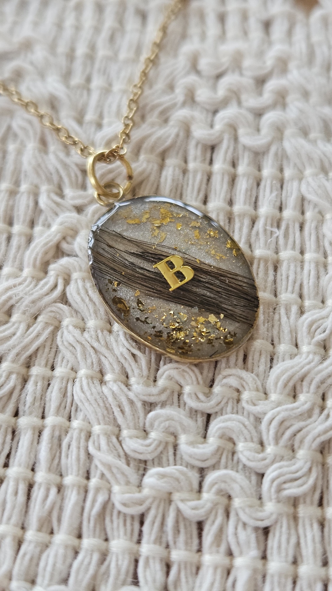 Ovaler Resin-Anhänger mit Tierfell, Blattgold und goldenem Buchstaben B auf feinem Strick